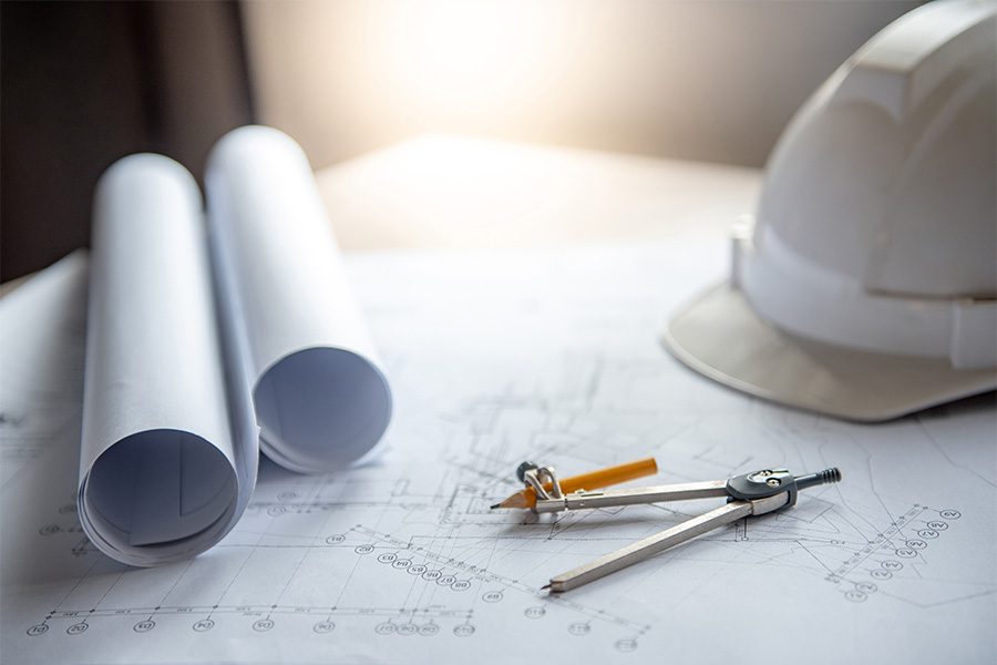 Specialized Business Insurance - View of Construction Hat and New Building Blue Prints on Desk